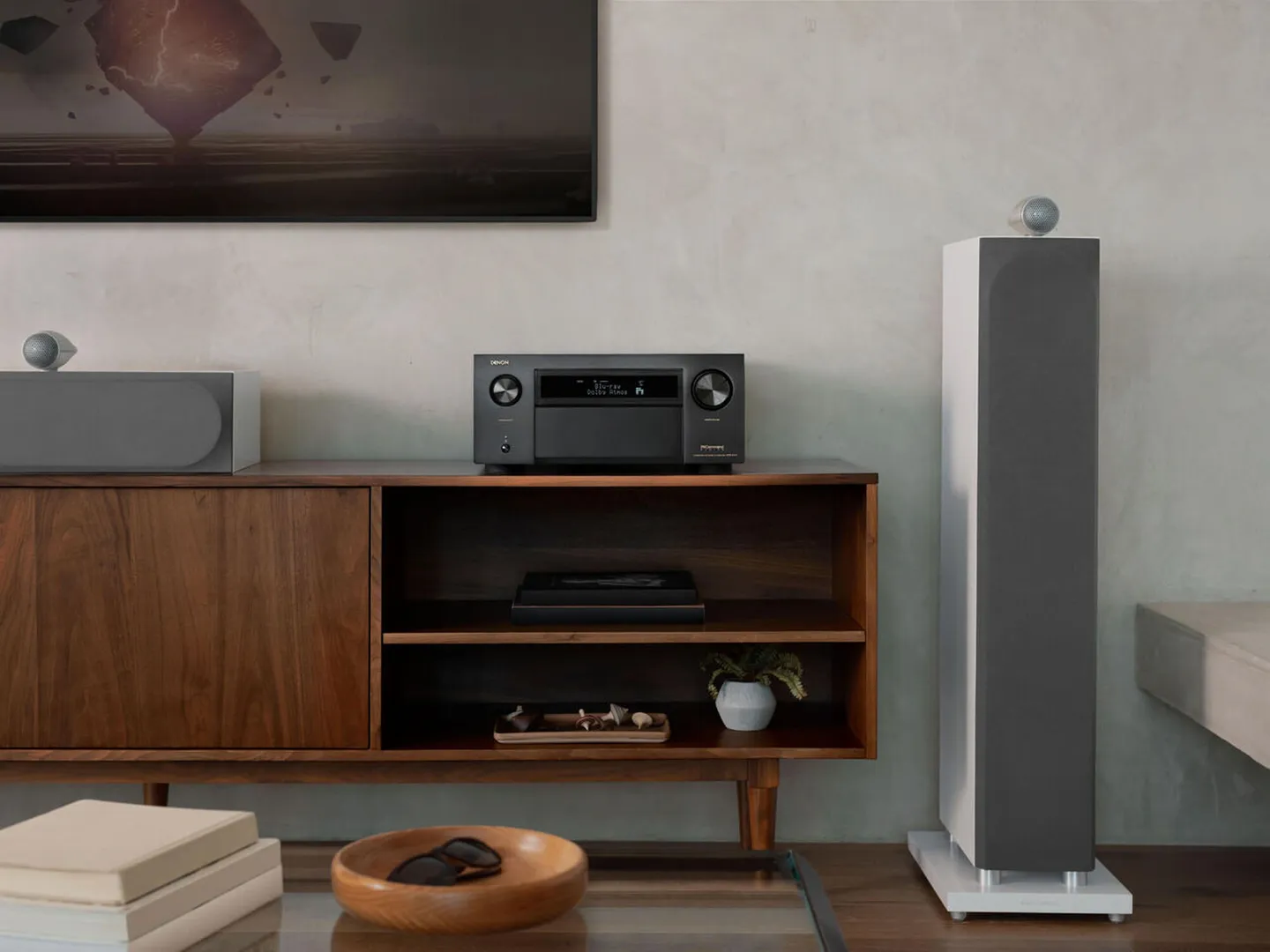 Denon AVC-A1H en un living junto a una columna de piso y un bafle central
