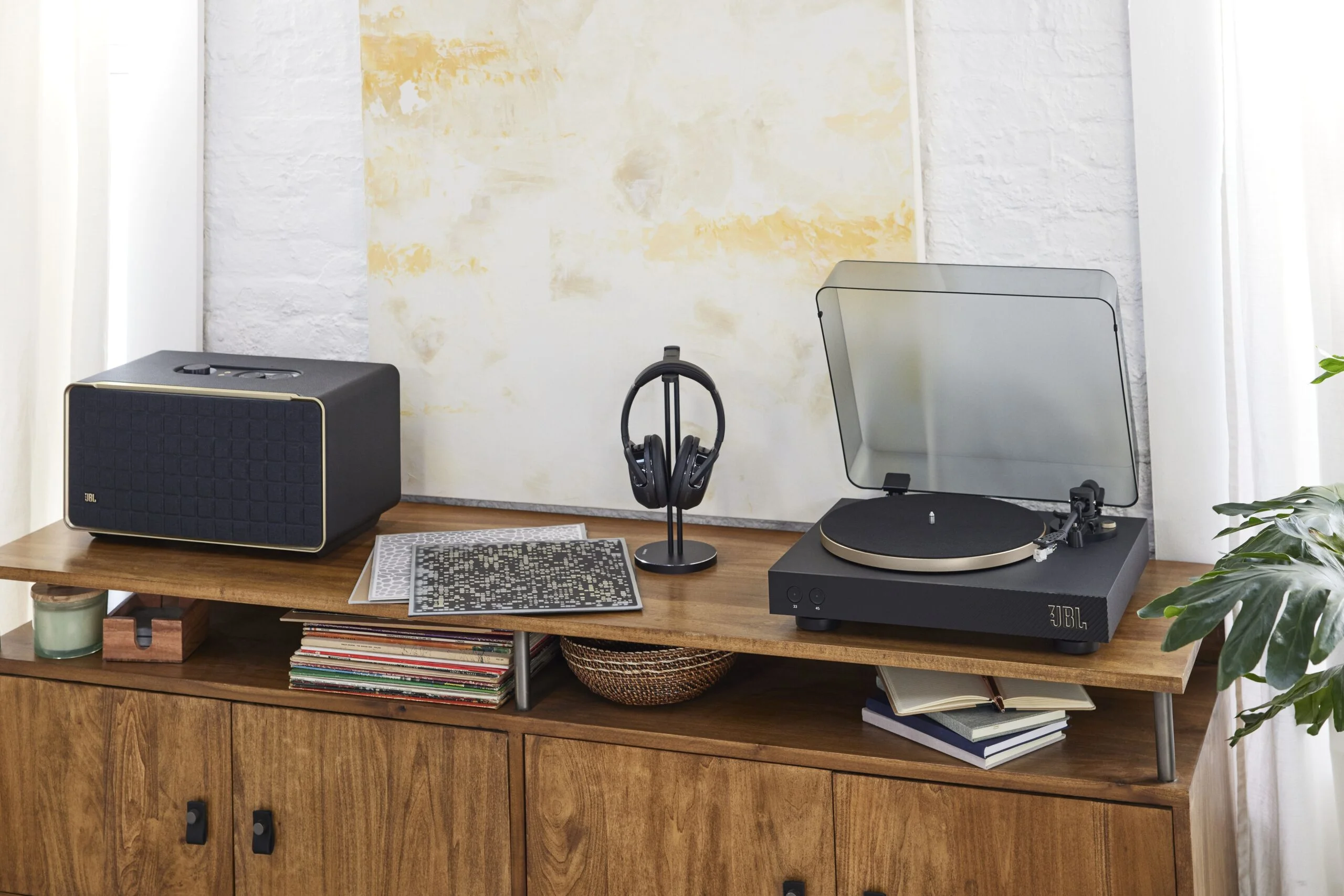 Bandeja giradiscos JBL Spinner BT en un living junto a un parlante y auriculares