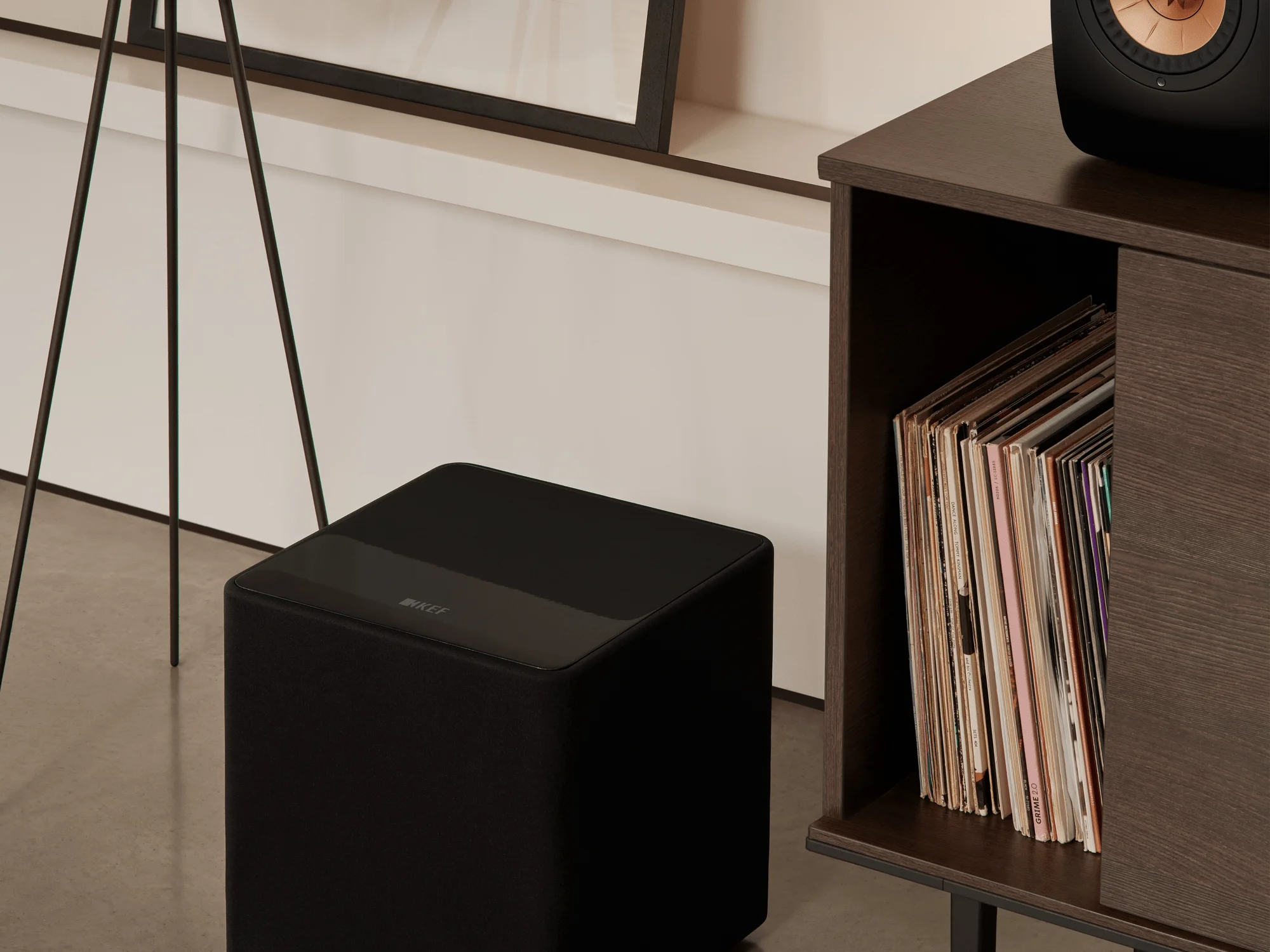 Subwoofer KEF Kube 10 MIE en un living junto a un mueble con discos de vinilo