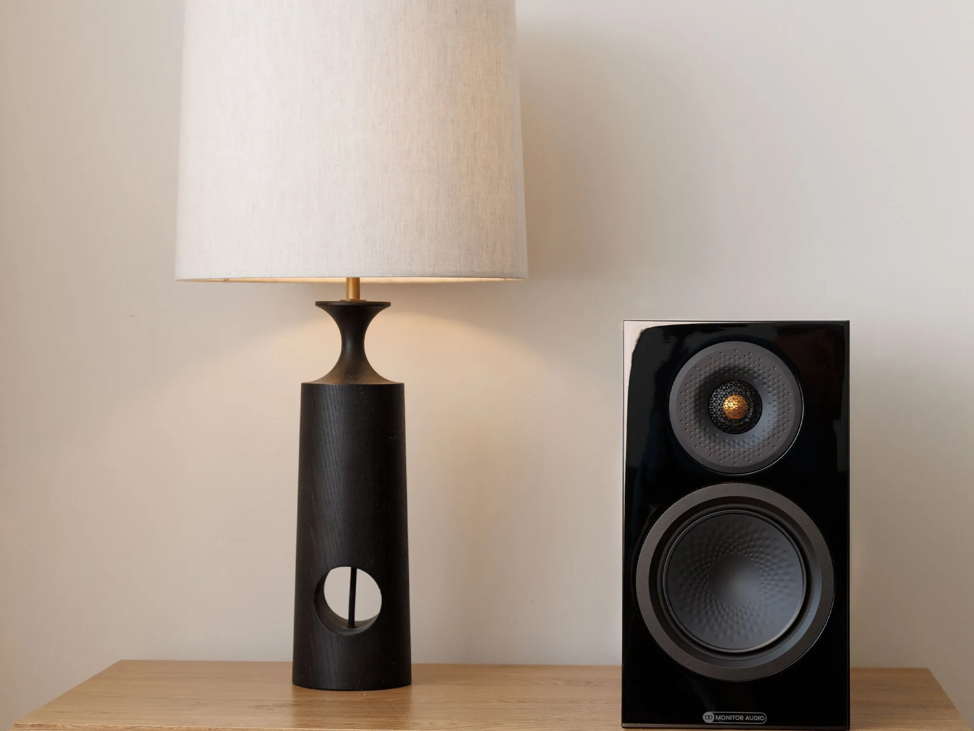 Bafle de estante Monitor Audio Silver 50 8G sobre un mueble junto a una lámpara