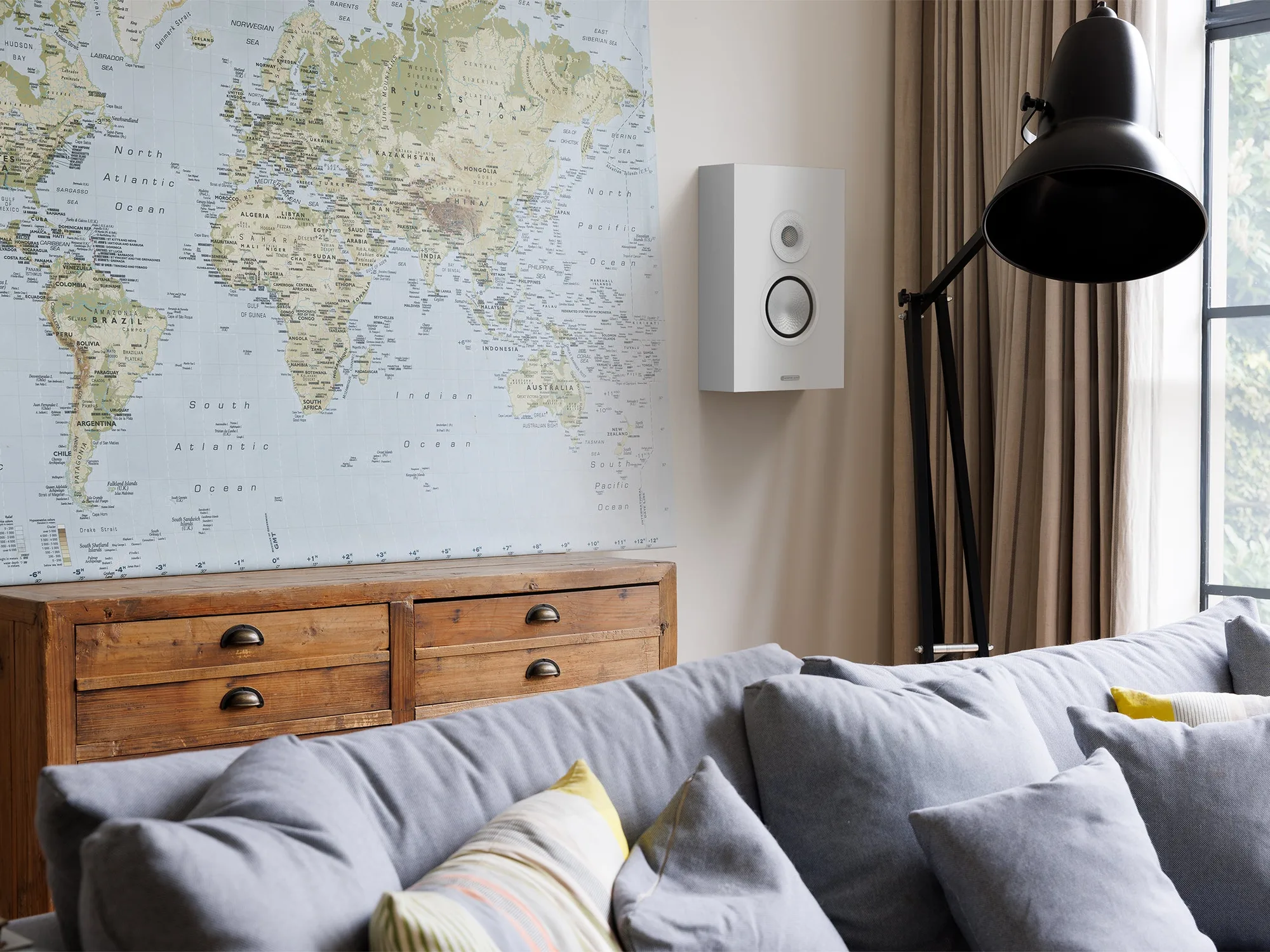 Bafle de pared Monitor Audio Silver On-Wall 8G junto a un sillón